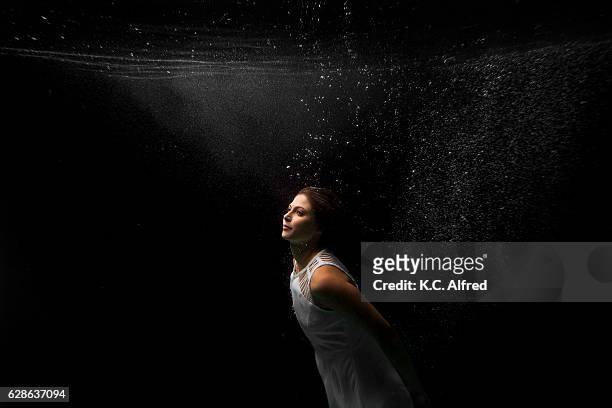 portrait of a female model underwater in a swimming pool with a black background in san diego, california. - swimsuit models girls stock-fotos und bilder