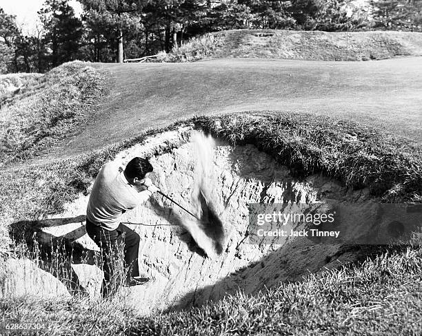 Golfer tries his luck getting out of the Devil's Hole, a sand trap on the 10th green of the Pine Valley Golf Club, Clementon, New Jersey, 1960s.