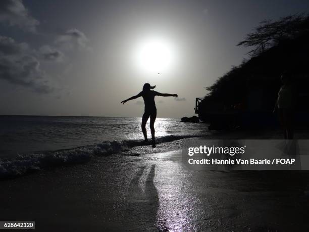 silhouette of girl jumping in ocean - hannie van baarle stockfoto's en -beelden