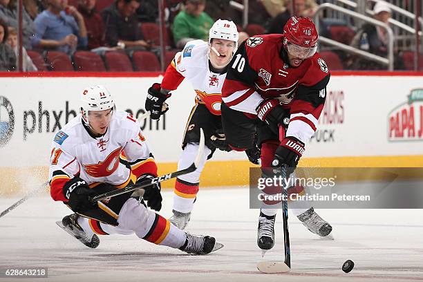 Anthony Duclair of the Arizona Coyotes skates with the puck ahead of Mikael Backlund and Matthew Tkachuk of the Calgary Flames during the first...
