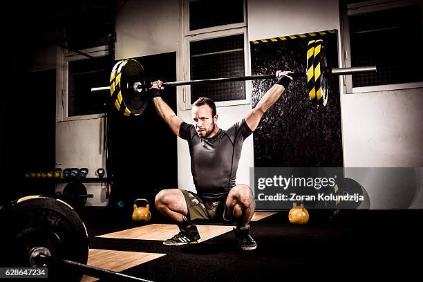 young man on cross training lifting weights - snatch weightlifting 個照片及圖片檔