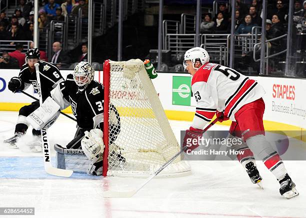 Jeff Skinner of the Carolina Hurricanes skates around the net with the puck as he is watched by Jeff Zatkoff of the Los Angeles Kings during the...