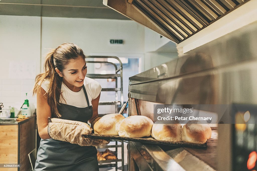 Bäcker zieht ein Tablett mit heißem Brot