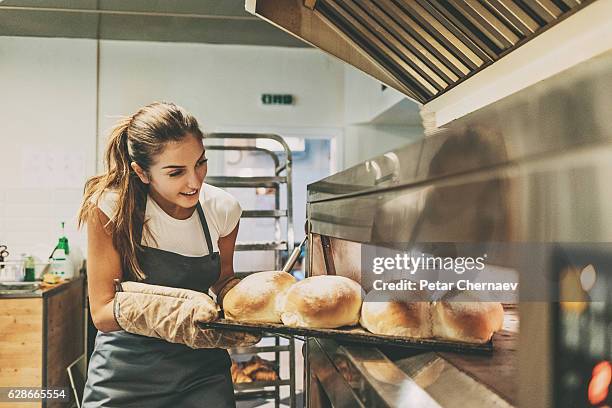 baker pulling a tray with hot bread - bread shop stock pictures, royalty-free photos & images