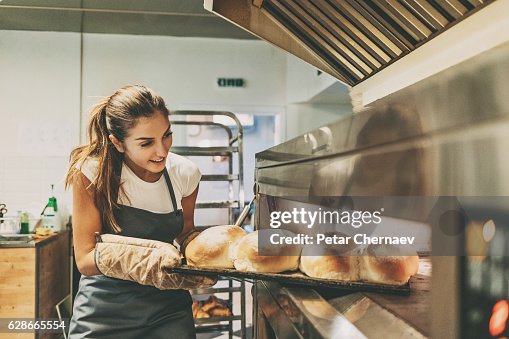 Baker pulling a tray with hot bread Baker pulling a tray with hot bread