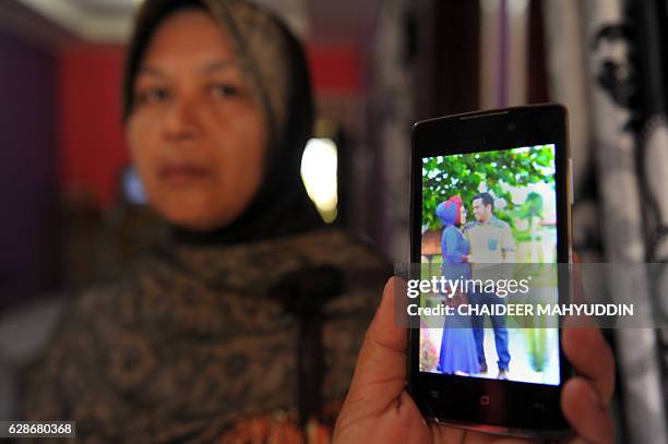 In this photograph taken on December 8 the mother of Yusra Fitriani shows a pre-wedding portrait photo of her daughter and groom in Pidie Jaya, Aceh...