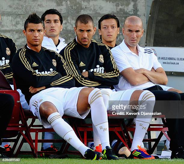 Real Madrid players Cristiano Ronaldo Karim Benzema and Zinedine Zidane, Real Madrid Director of Football, follow the action from bench during the...