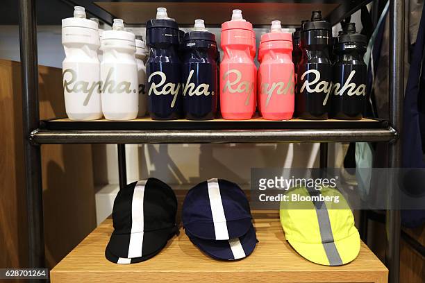 Branded water bottles, also known as bidons, and cycling caps sit on display at the Rapha Racing Ltd. Cycle club on Brewer Street in London, U.K., on...