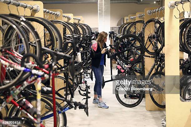 An employee removes a bicycle from its hanger at the Rapha Racing Ltd. Headquarters office in London, U.K., on Thursday, Nov. 10, 2016. To keep ahead...
