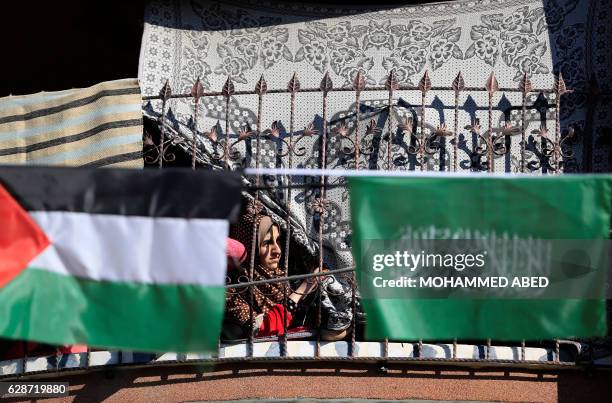 Palestinian woman look out at supporters of the Palestinian Hamas movement attending a rally to commemorate the 29th anniversary of the movement on...