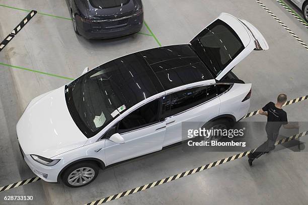 An employee passes a new Tesla Model X sports utility vehicle following assembly for the European market at the Tesla Motors Inc. Factory in Tilburg,...