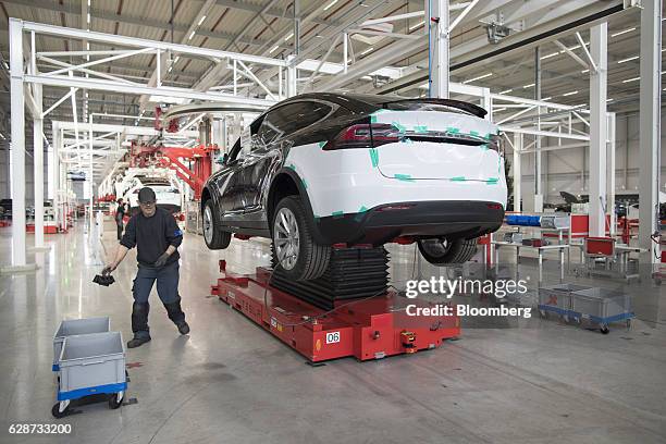 Tesla Model X electric sports utility vehicle stands on a hydraulic platform as employees work on the assembly line at the Tesla Motors Inc. Factory...