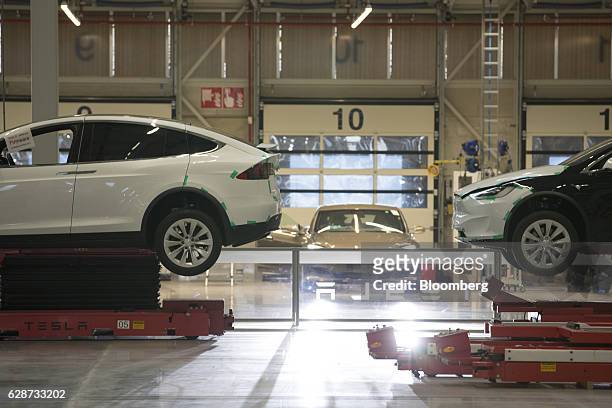 Tesla Model X sports utility vehicles stand on hydraulic platforms during assembly for the European market at the Tesla Motors Inc. Factory in...