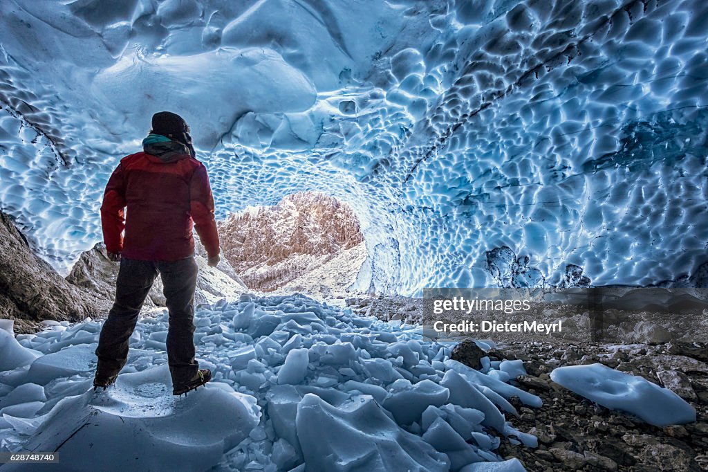 Hiker with crampon looking out of  ice cave - Berchtesgaden