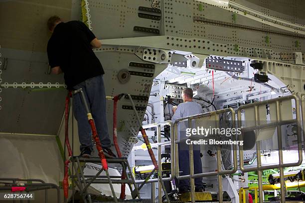 Employees work on the exterior of a Boeing Co. Dreamliner 787 plane at the company's midbody operations facility in North Charleston, South Carolina,...