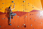 Attractive woman climbing up the wall in gym