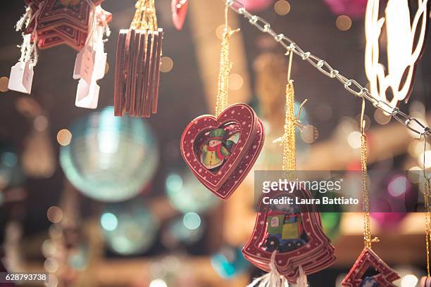 christmas shopping - little wooden ornaments for sale hanging in a christmas market stall - marché de noël photos et images de collection