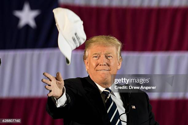 President-elect Donald Trump tosses a 'Make America Great Again' hat into the crowd while speaking at the Dow Chemical Hangar, December 9, 2016 in...