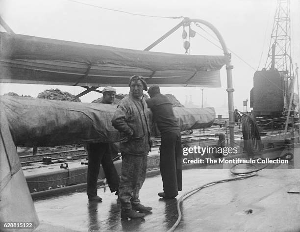 Crew members from Royal Navy Ship HMS Dido an Eclipse class cruiser on deck preparing to refuel HMS Dido with coal at Portland Harbour off Dorset on...