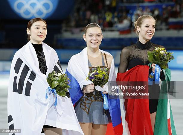 Russia - Women's figure skating medalists wrap themselves in their countries' flags on Feb. 20 at the Sochi Winter Olympic Games. From left: Silver...