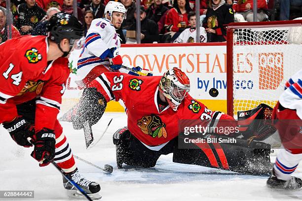 Goalie Scott Darling of the Chicago Blackhawks watches the puck while guarding the net, as Marek Hrivik of the New York Rangers skates in the...