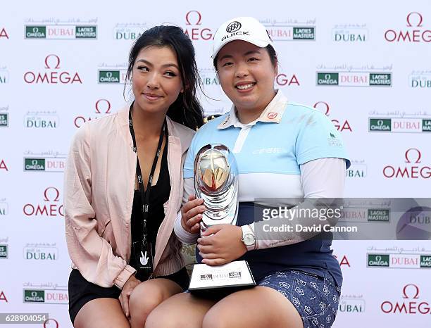 Shangshan Feng of China holds the trophy with Muni He of China after her victory during the final round of the 2016 Omega Dubai Ladies Masters on the...