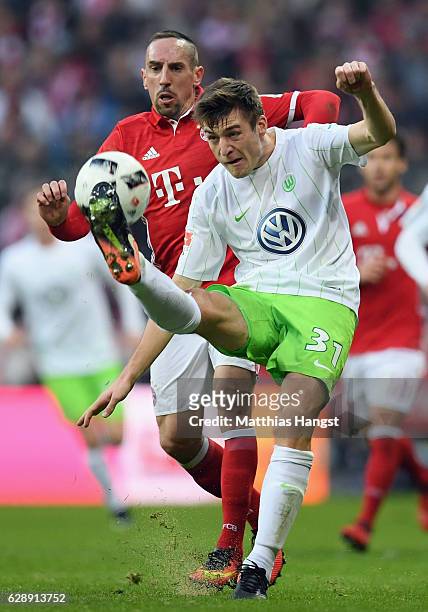 Robin Knoche of Wolfsburg clears the ball ahead of Franck Ribery of Muenchen during the Bundesliga match between Bayern Muenchen and VfL Wolfsburg at...