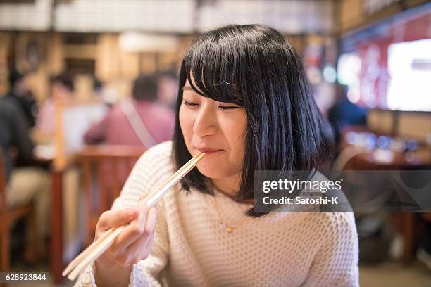 young woman eating japanese food with chopsticks - japanese chopsticks stock pictures, royalty-free photos & images