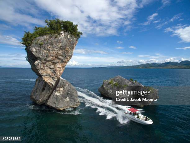speedboat passing by a small rock island - speed boat top view stock pictures, royalty-free photos & images