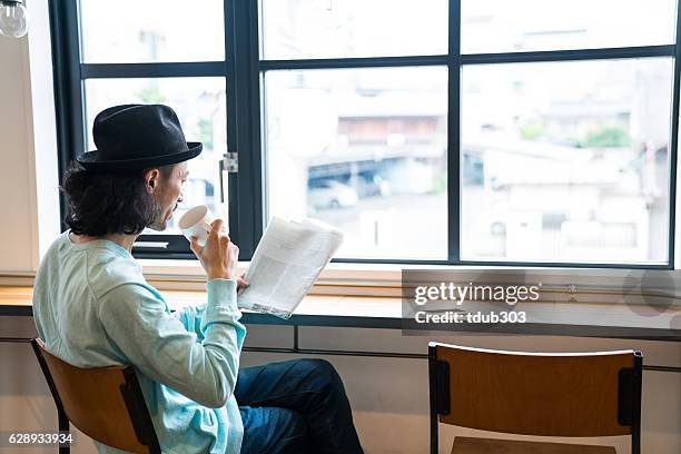 uomo maturo che legge un giornale al bar mentre beve caffè - coffee and news paper foto e immagini stock