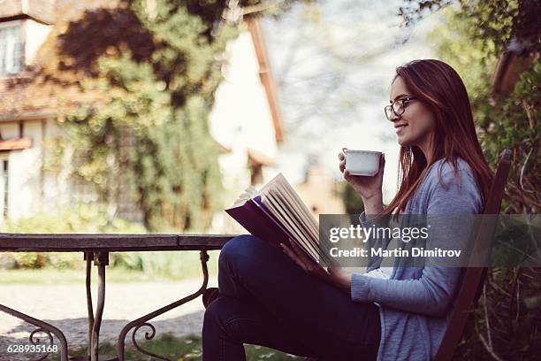 hausfrau liest ein buch auf der veranda - french garden stock-fotos und bilder
