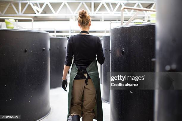 female worker walking through storage tanks in fish farm - aquacultuur stockfoto's en -beelden