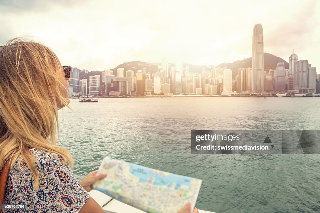 Caucasian young woman looks at Hong Kong city map