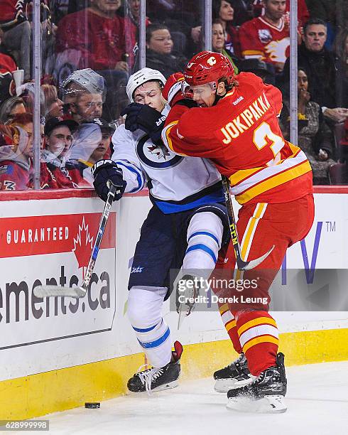 Jyrki Jokipakka of the Calgary Flames checks Andrew Copp of the Winnipeg Jets during an NHL game at Scotiabank Saddledome on December 10, 2016 in...