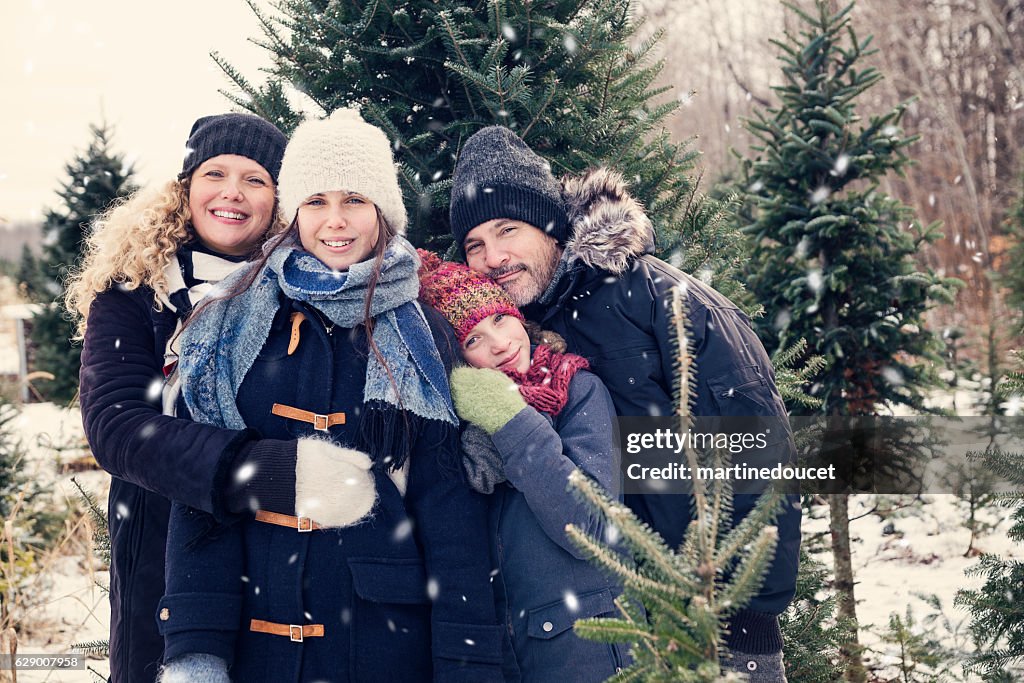 Real family portrait in winter with fir trees and snow.