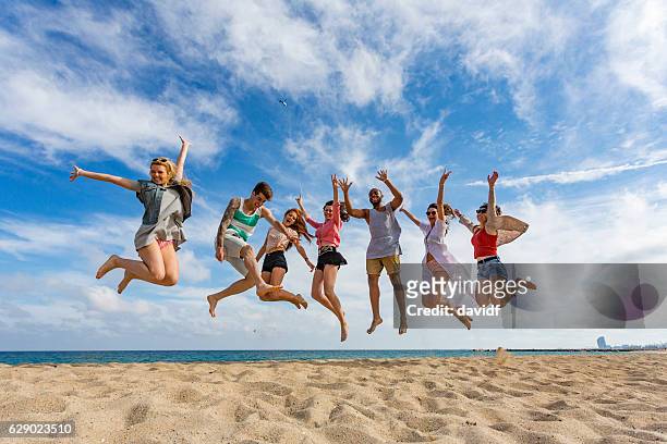 feiern gruppe von freunden springen am strand - junge frau strand sand springen stock-fotos und bilder