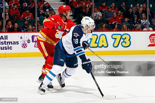 Jyrki Jokipakka of the Calgary Flames skates against Bryan Little of the Winnipeg Jets during an NHL game on December 10, 2016 at the Scotiabank...