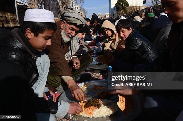 Afghan men and boys eat during celebrations marking the birth anniversary of the Prophet Mohammed in Herat on December 11, 2016. The birth of the...