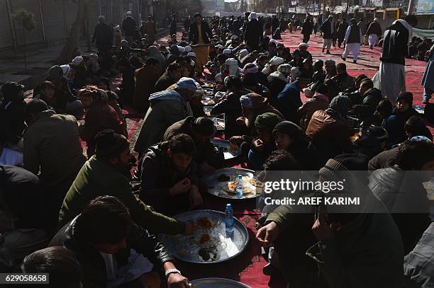 Afghan men and boys eat during celebrations marking the birth anniversary of the Prophet Mohammed in Herat on December 11, 2016. The birth of the...