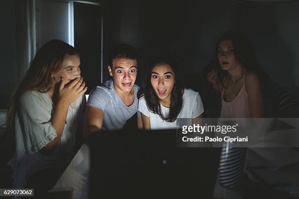 estudiantes universitarios viendo películas de miedo en la computadora portátil - scary movie fotografías e imágenes de stock