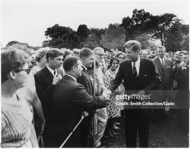 President John F Kennedy greets volunteers with the Peace Corps on the south lawn at the White House, Washington, DC, August 9, 1962. Image courtesy...
