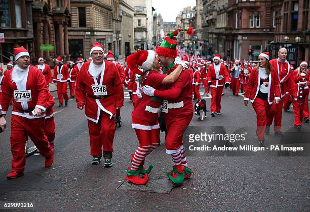 Couple embrace as runners in Santa costumes take part in the Glasgow Santa Dash to raise funds for the Beatson Cancer Charity.
