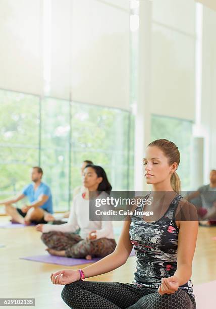 serene woman in lotus position with eyes closed in yoga class - ギアナ・ムドラー ストックフォトと画像