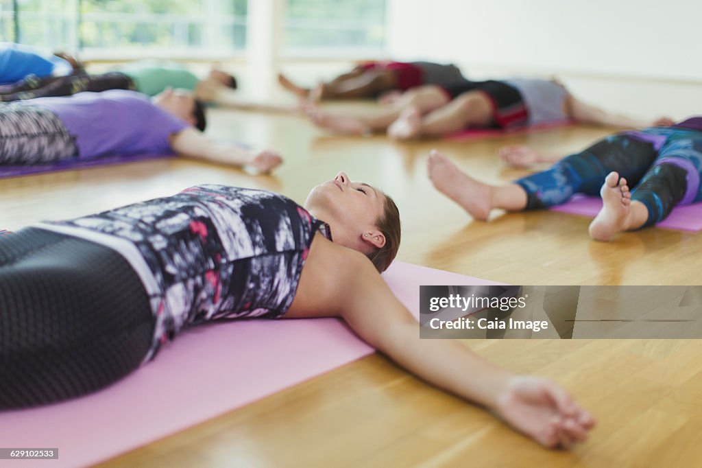 Serene woman in corpse pose in yoga class