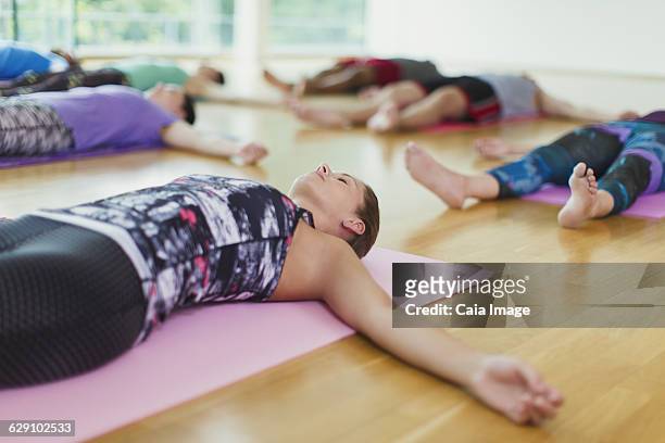 serene woman in corpse pose in yoga class - savasana stock pictures, royalty-free photos & images