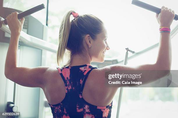 fit woman doing lat pulldowns on equipment at gym - lat pulldown imagens e fotografias de stock