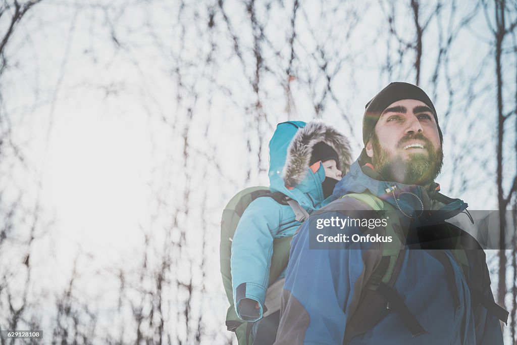 Padre zaino in spalla escursioni con bambino nella foresta invernale