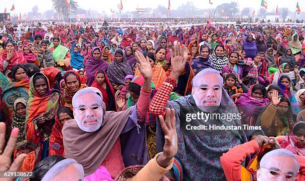 Supporters listen to Prime Minister Narendra Modi as he delivers a speech through mobile phone during a Parivartan rally, on December 11, 2016 in...