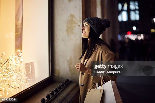 christmas shopping looking at a window shop. - shop window stock pictures, royalty-free photos & images