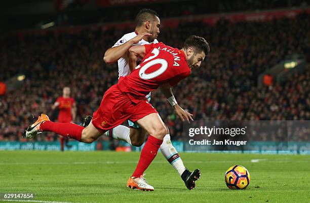 Adam Lallana of Liverpool is challenged by Dimitri Payet of West Ham United in the penalty area during the Premier League match between Liverpool and...